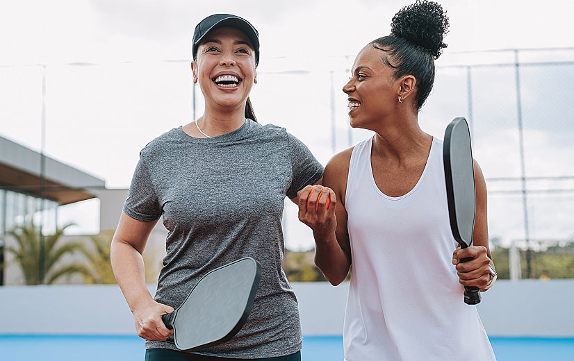 Two women enjoying tennis together outdoors.