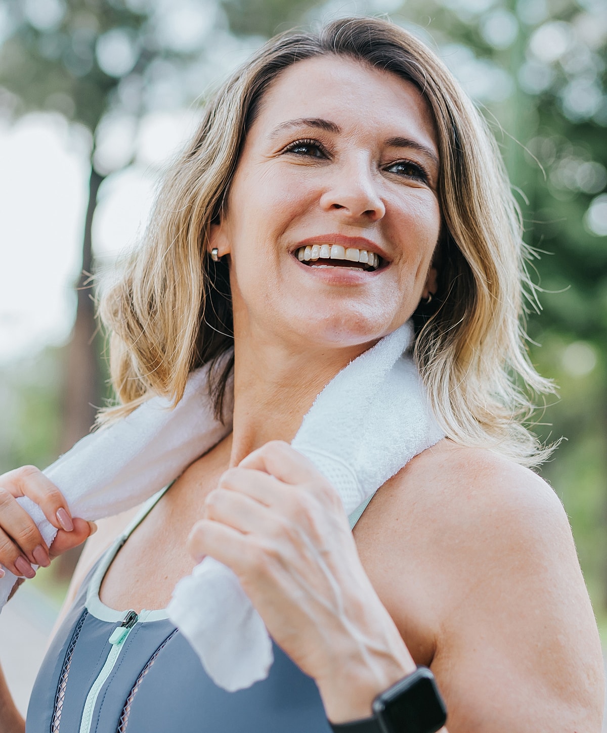 Smiling woman in workout attire with towel.